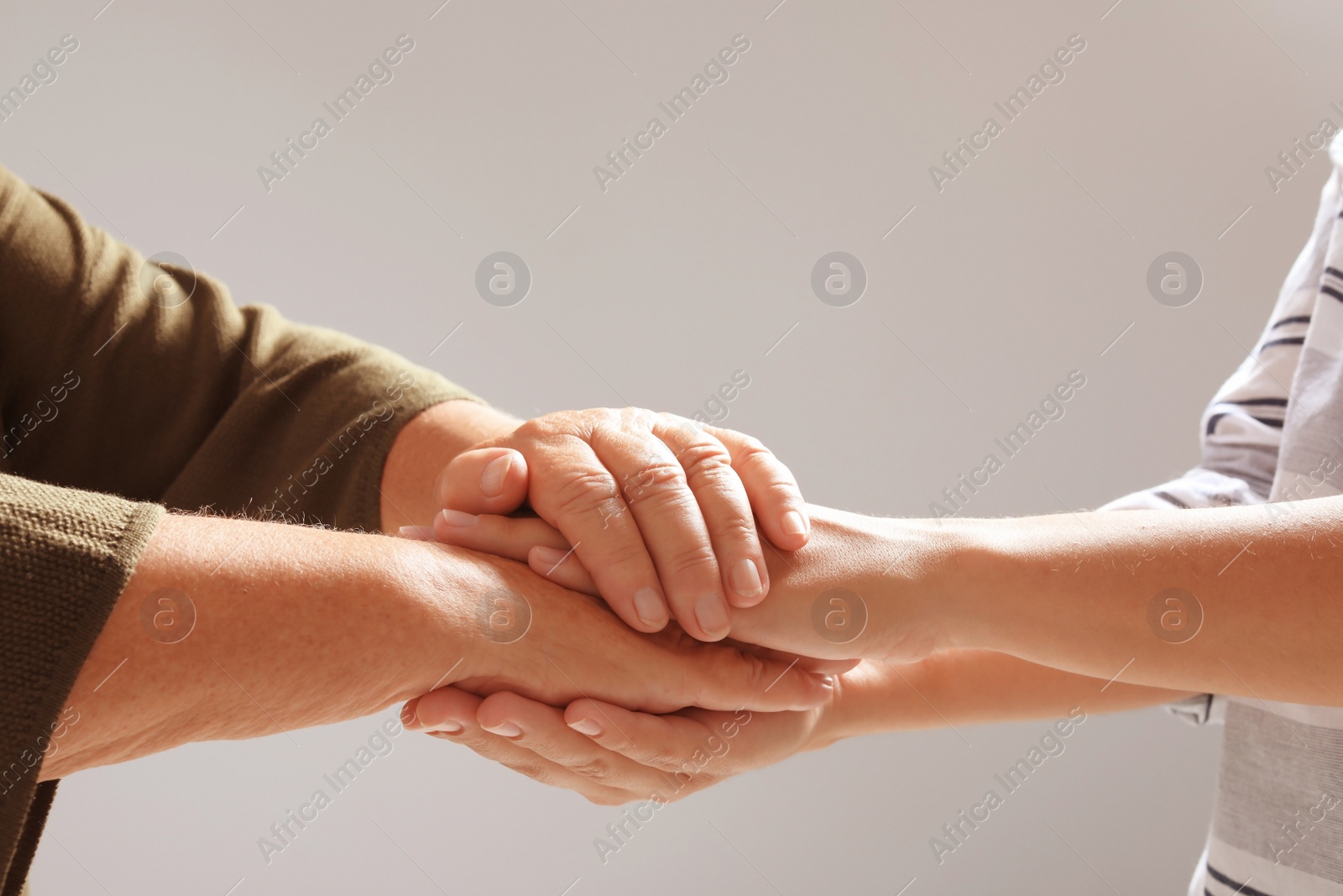 Photo of Helping hands on grey background, closeup. Elderly care concept