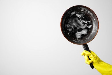 Woman holding dirty frying pan on white background, closeup. Space for text