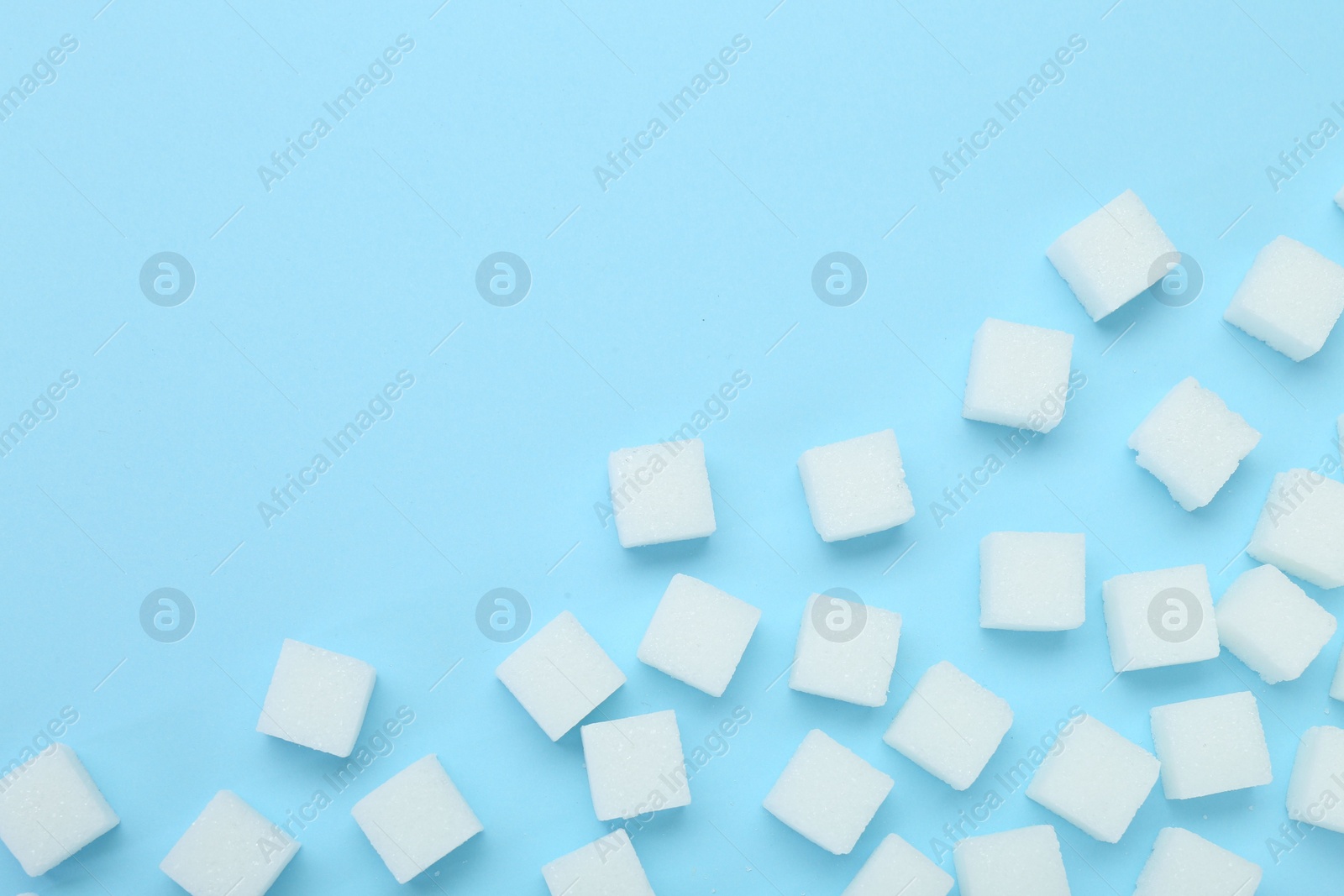 Photo of White sugar cubes on light blue background, top view. Space for text