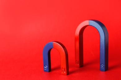 Photo of Red and blue horseshoe magnets on color background. Space for text