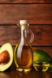Photo of Cooking oil and fresh ripe avocados on wooden table