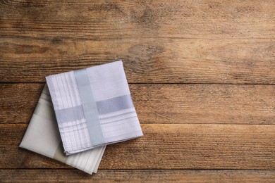Photo of Different handkerchiefs folded on wooden table, flat lay. Space for text