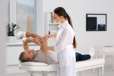 Professional orthopedist examining patient's arm in clinic