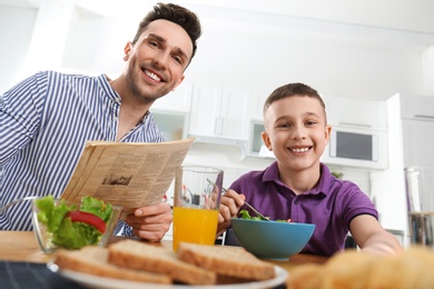 Photo of Dad and son having breakfast together in kitchen