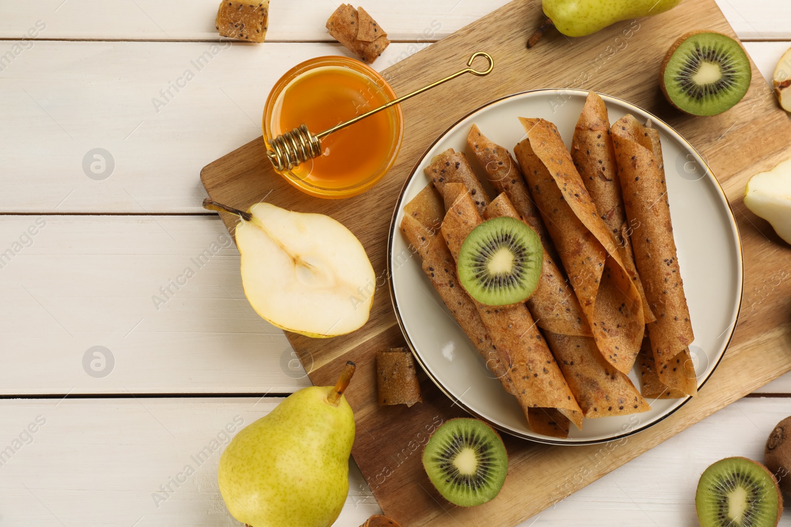 Photo of Flat lay composition with delicious fruit leather rolls on white wooden table