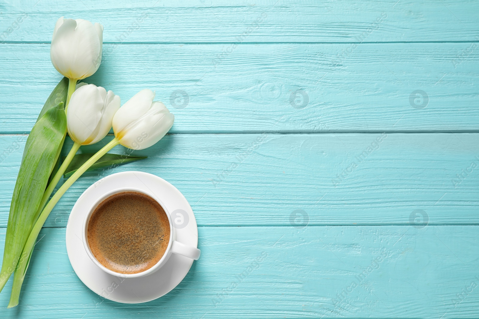 Photo of White tulips and coffee on light blue wooden table, flat lay with space for text. Good morning