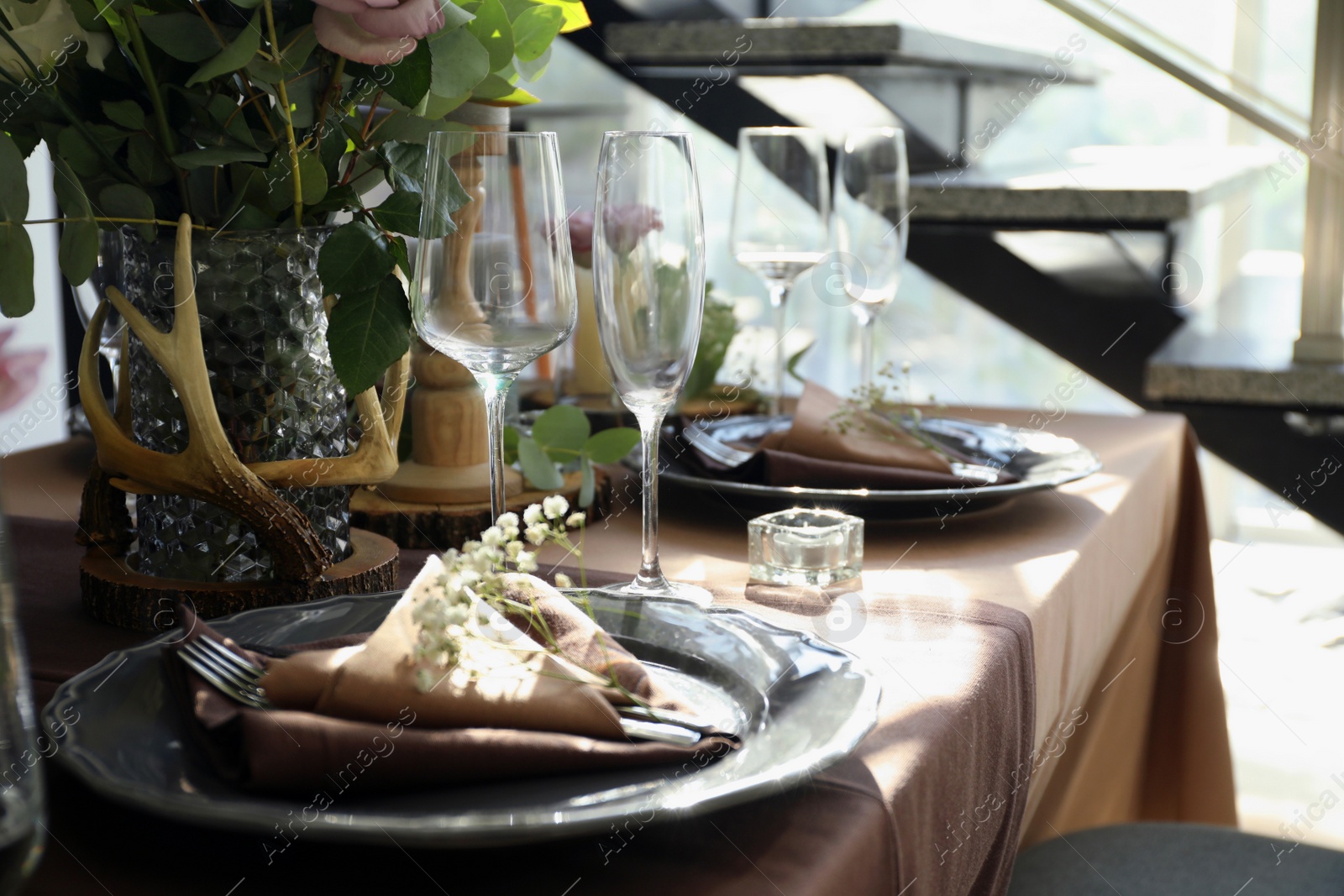 Photo of Festive table setting with beautiful tableware and floral decor in restaurant