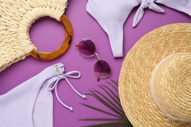 Photo of Flat lay composition with stylish straw hat and beach accessories on purple background