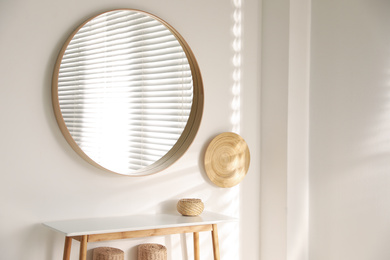 Stylish round mirror hanging on white wall in room