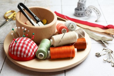 Spools of threads and sewing tools on light tiles