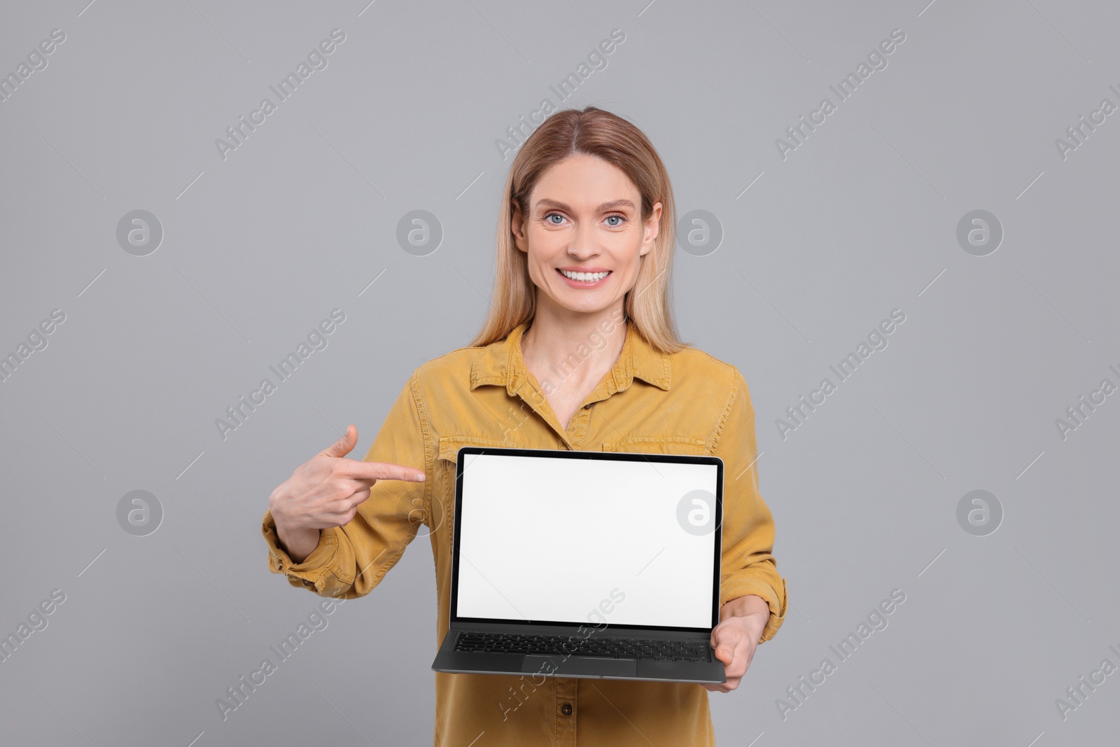 Photo of Happy woman showing laptop on light grey background