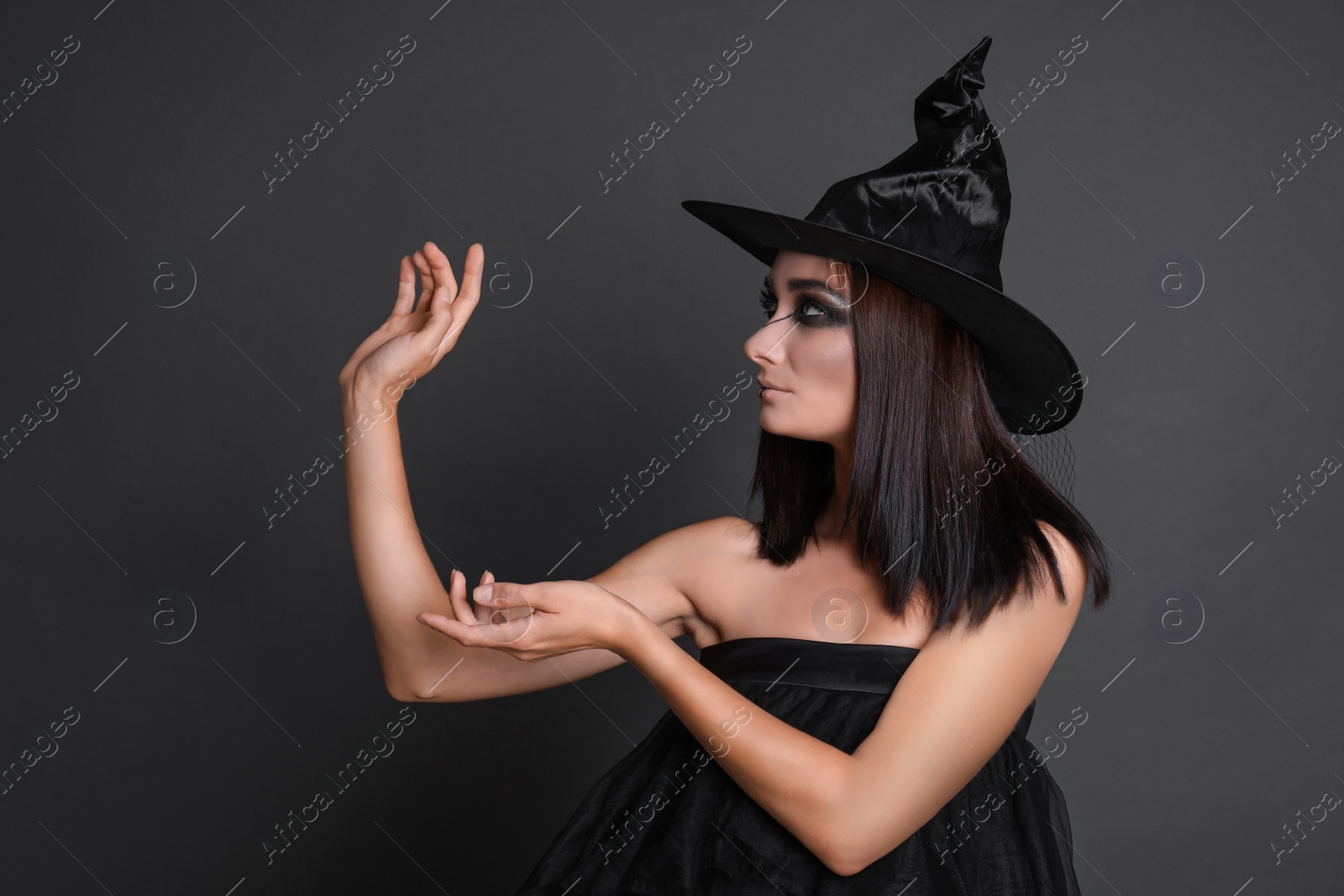 Photo of Mysterious witch wearing hat on black background