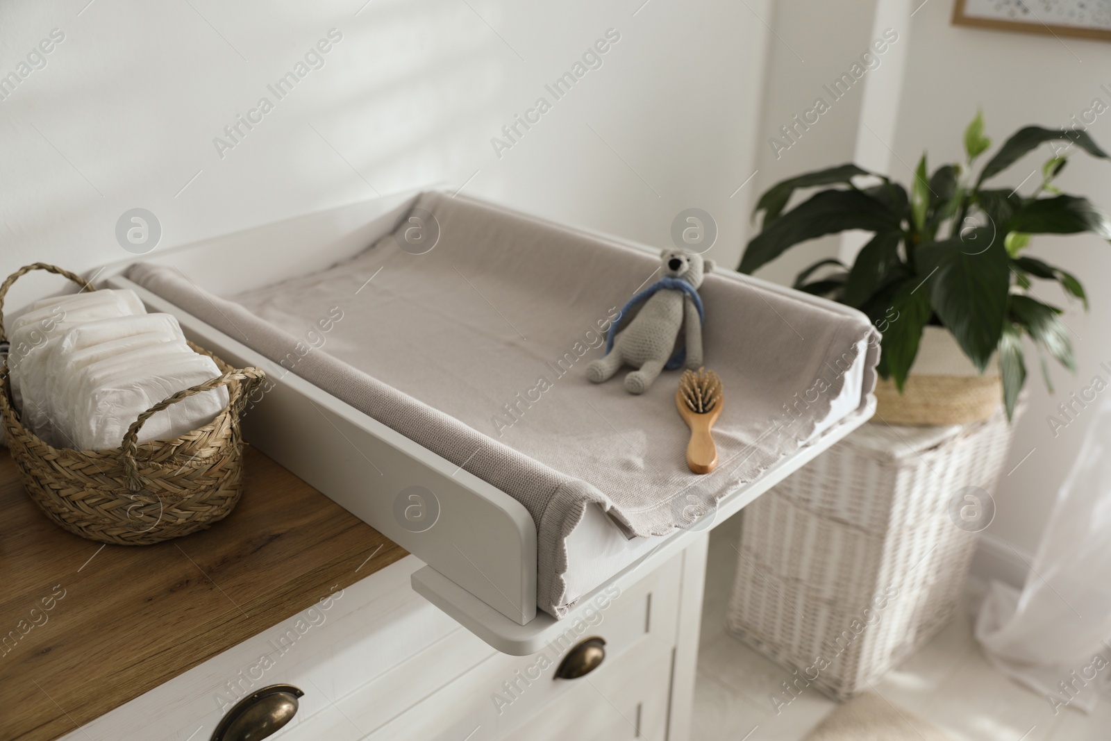 Photo of Chest of drawers with changing pad and tray in nursery. Baby room interior design