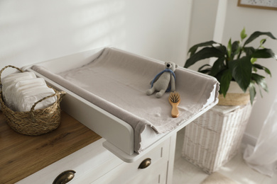 Chest of drawers with changing pad and tray in nursery. Baby room interior design