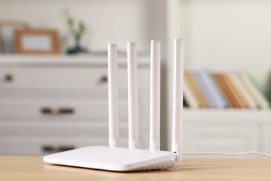 Photo of New white Wi-Fi router on wooden table indoors