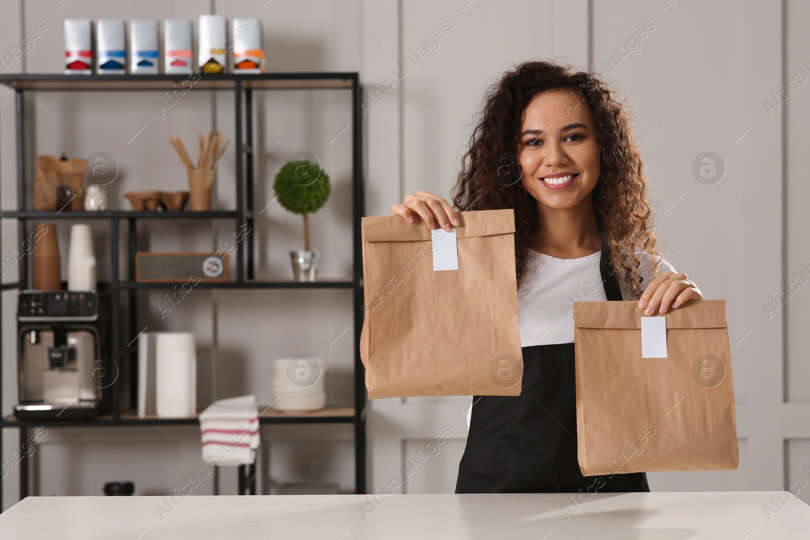 Photo of Worker with paper bags at counter in cafe, space for text