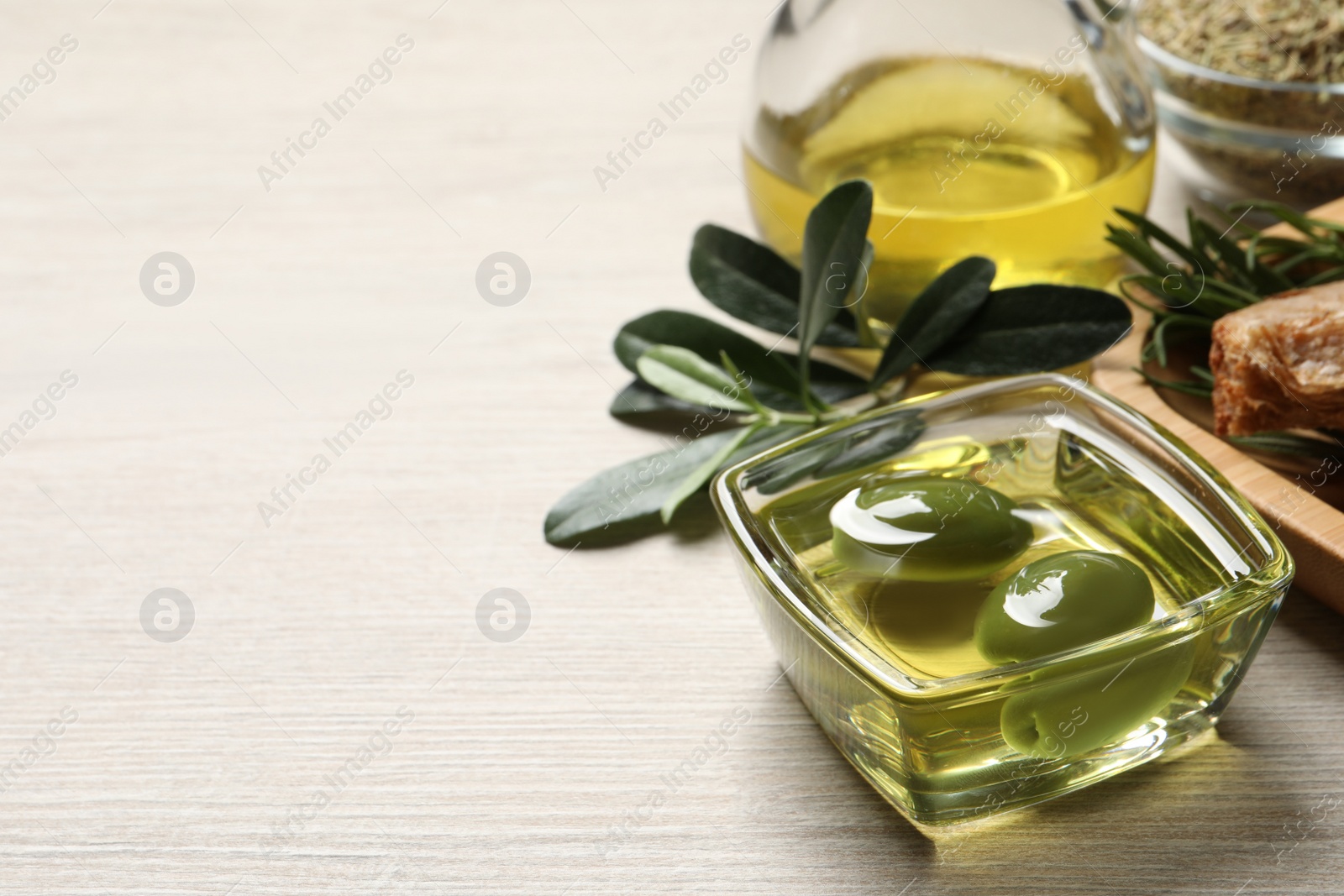 Photo of Fresh oil, ripe olives and green leaves on wooden table. Space for text