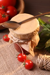 Photo of Jar of tasty tomato paste with spoon, ingredients and thread on table, above view