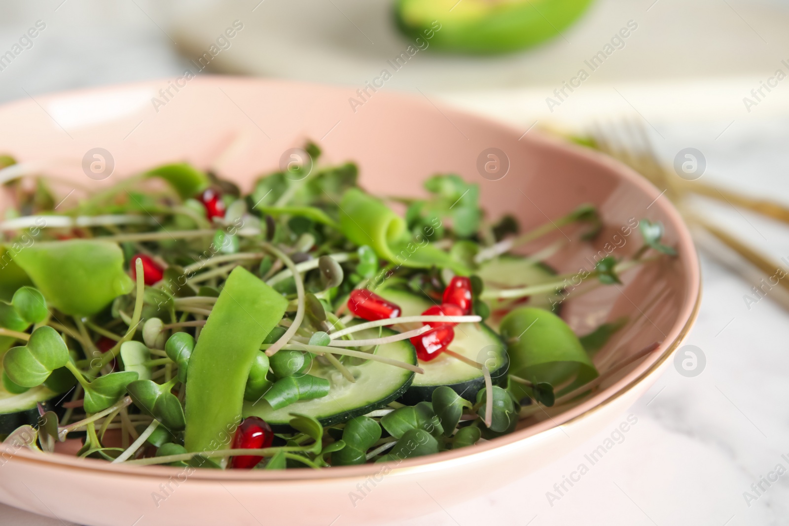 Photo of Salad with fresh organic microgreen in bowl on white table, closeup