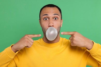 Photo of Portrait of man blowing bubble gum on green background