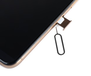 Mobile phone with Sim card in tray and ejector tool on white table, closeup