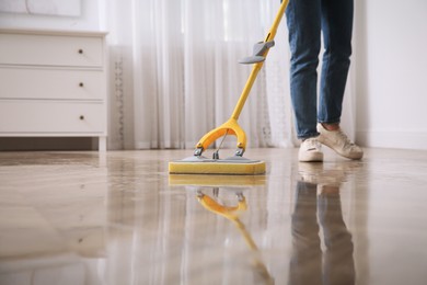Woman cleaning parquet floor with mop indoors, closeup. Space for text