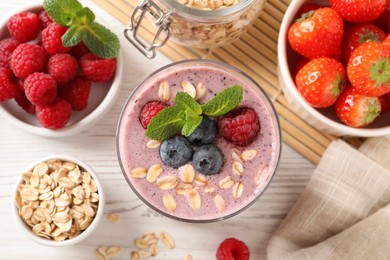 Photo of Flat lay composition with tasty oatmeal smoothie and berries on white wooden table