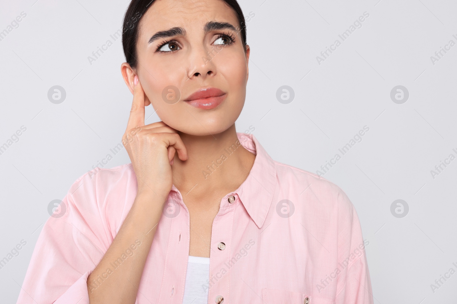 Photo of Young woman suffering from ear pain on light grey background