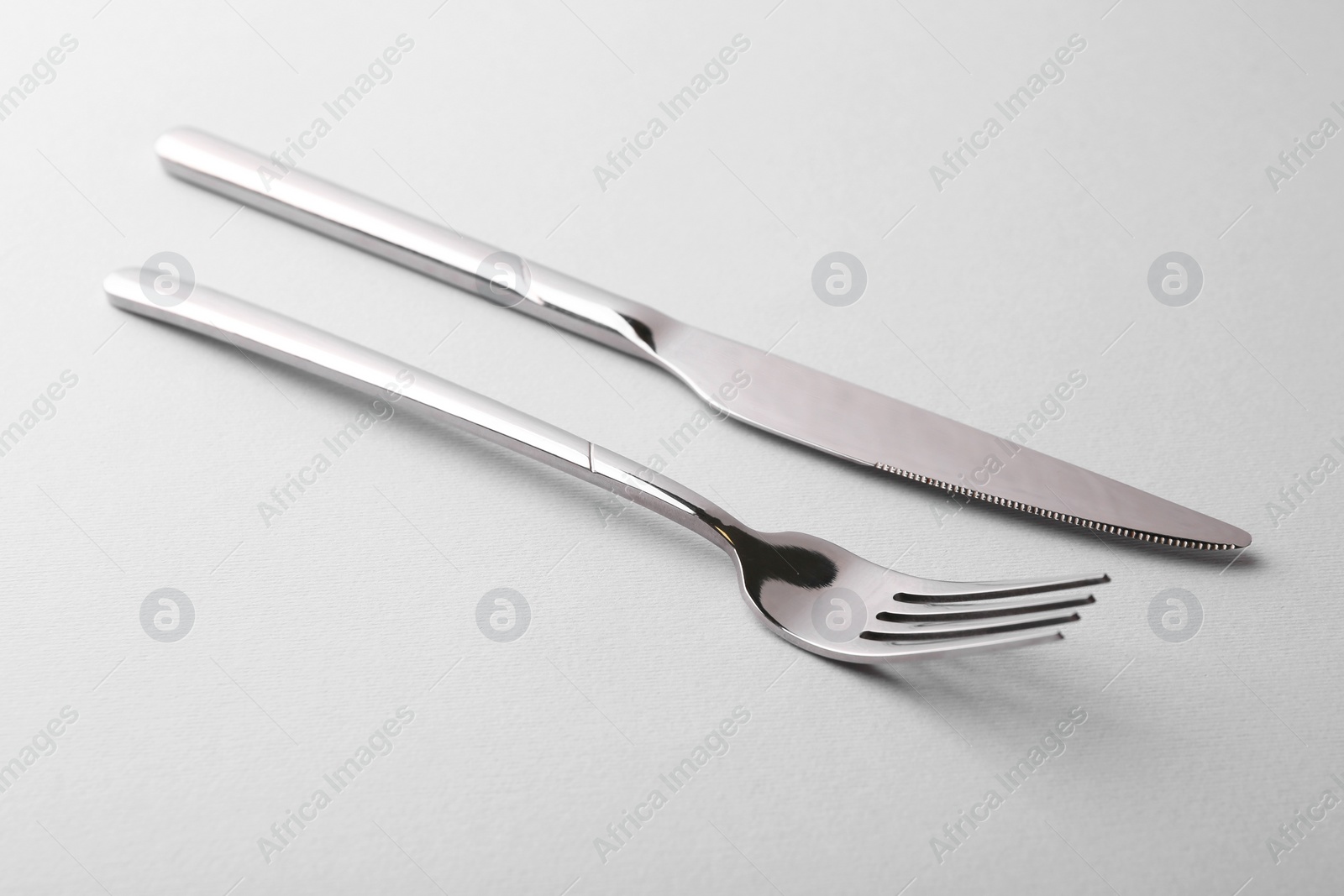 Photo of Stylish cutlery. Silver knife and fork on gray background