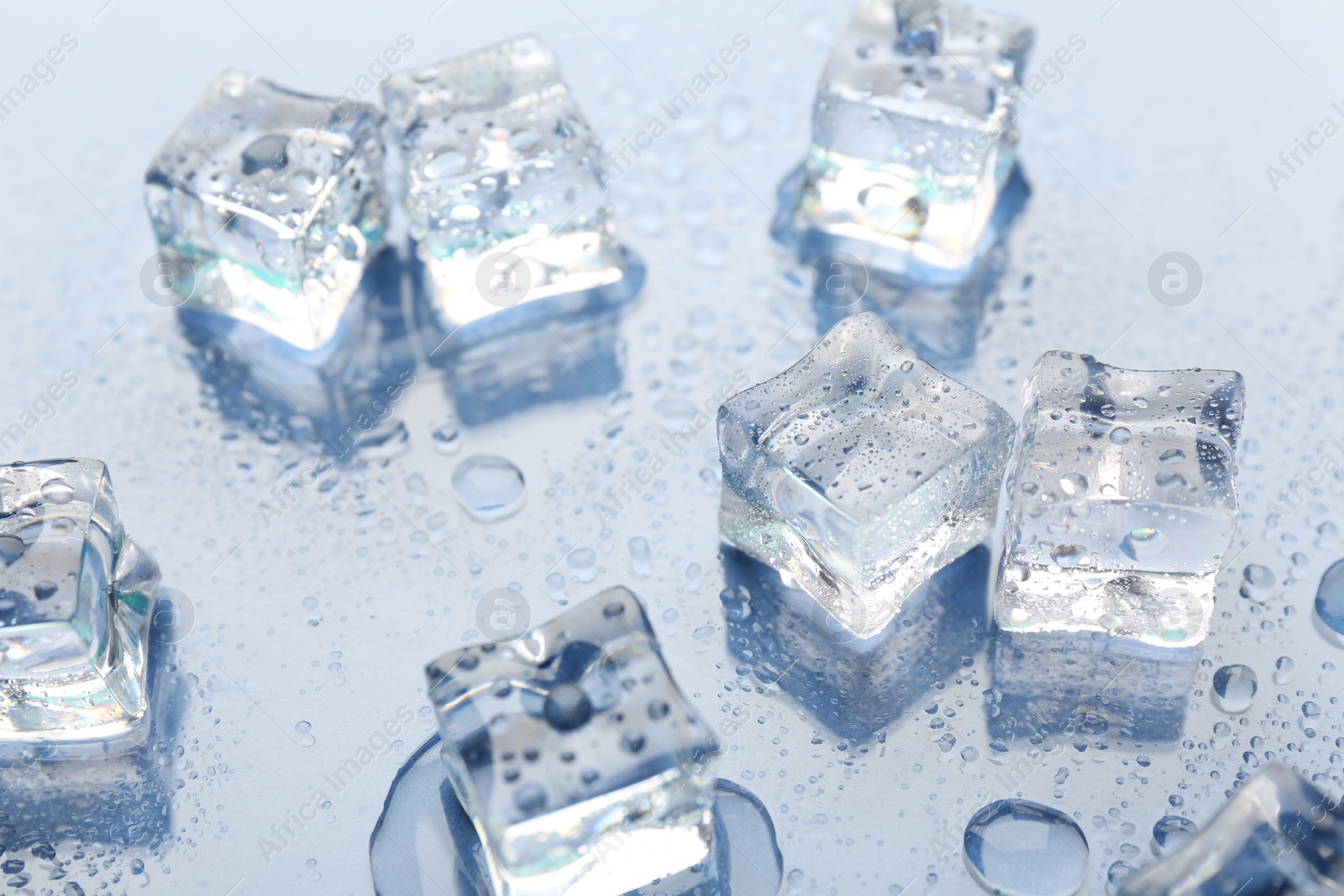 Photo of Melting ice cubes and water drops on light background, closeup