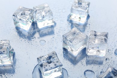 Photo of Melting ice cubes and water drops on light background, closeup