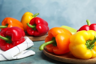 Photo of Fresh ripe bell peppers on wooden table against light blue background