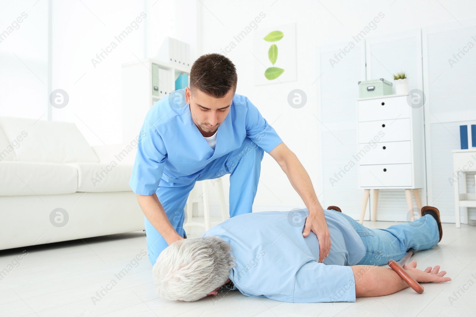 Photo of Young doctor giving first aid to senior man with heart attack in clinic