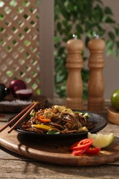 Photo of Stir-fry. Tasty noodles with meat and vegetables served on wooden table