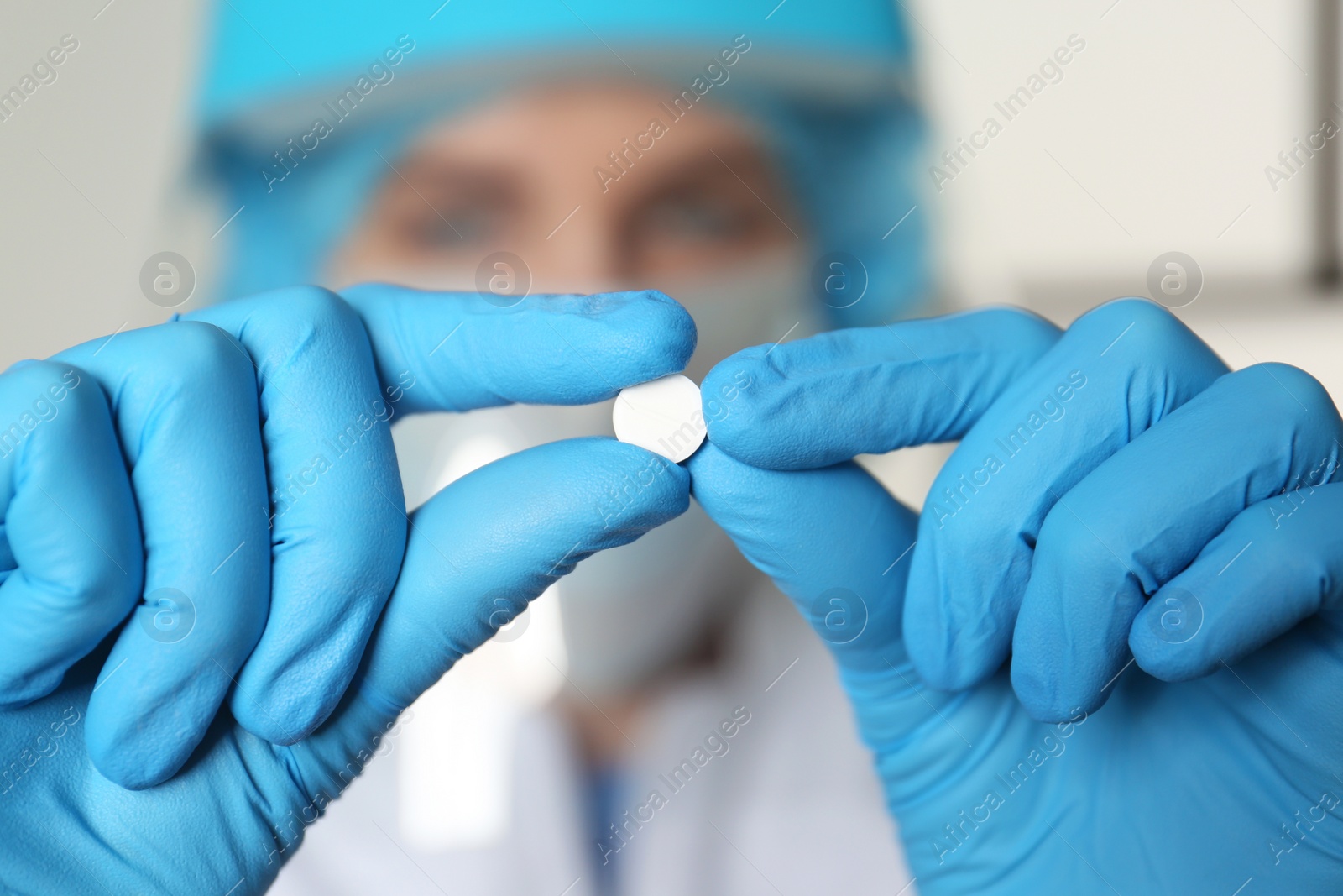 Photo of Scientist in protective gloves holding pill, closeup view