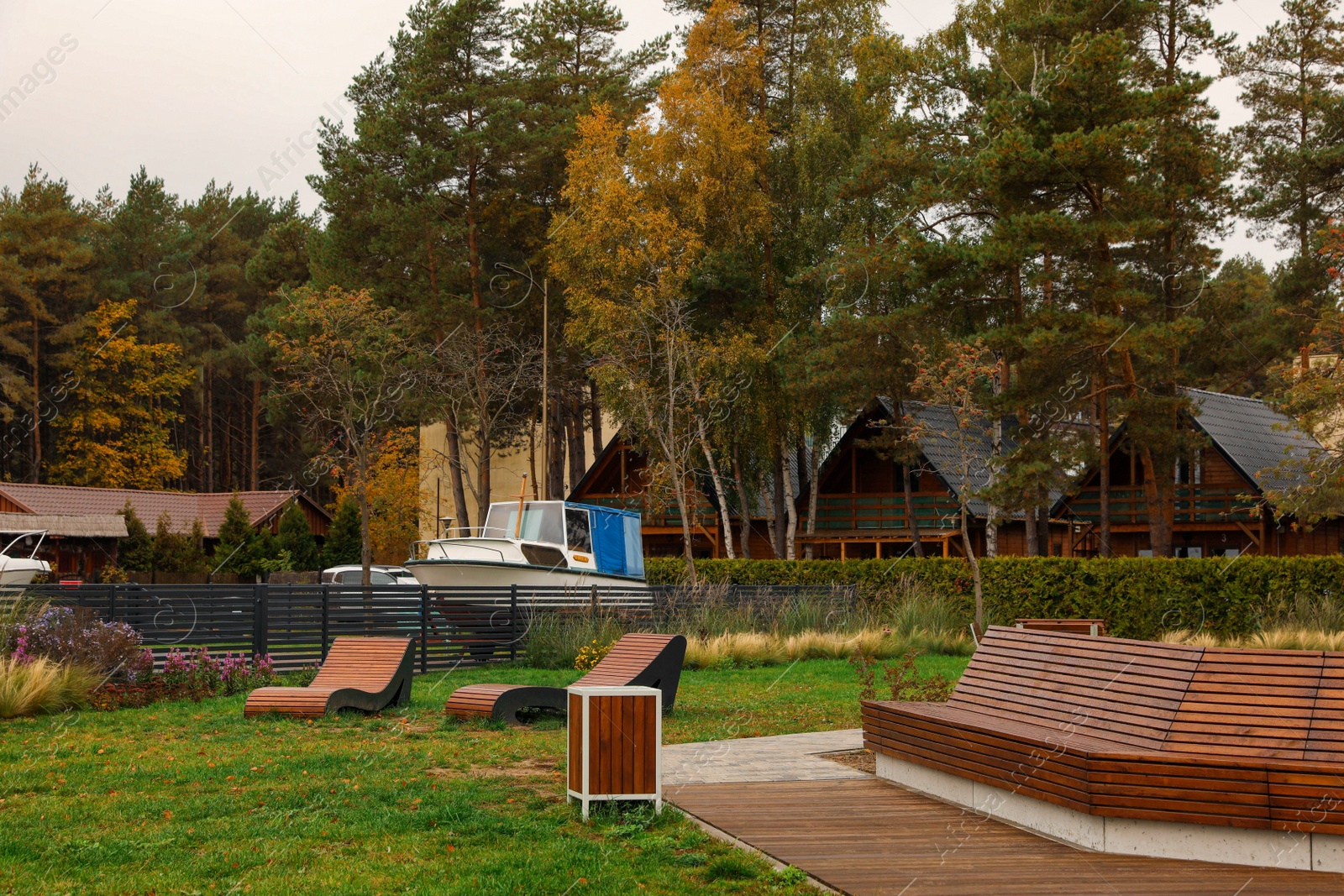 Photo of Beautiful park with comfortable wooden benches, houses and trees