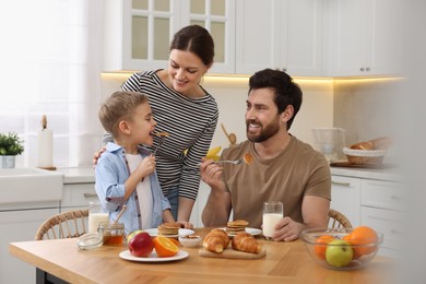 Photo of Happy family having breakfast at table in kitchen