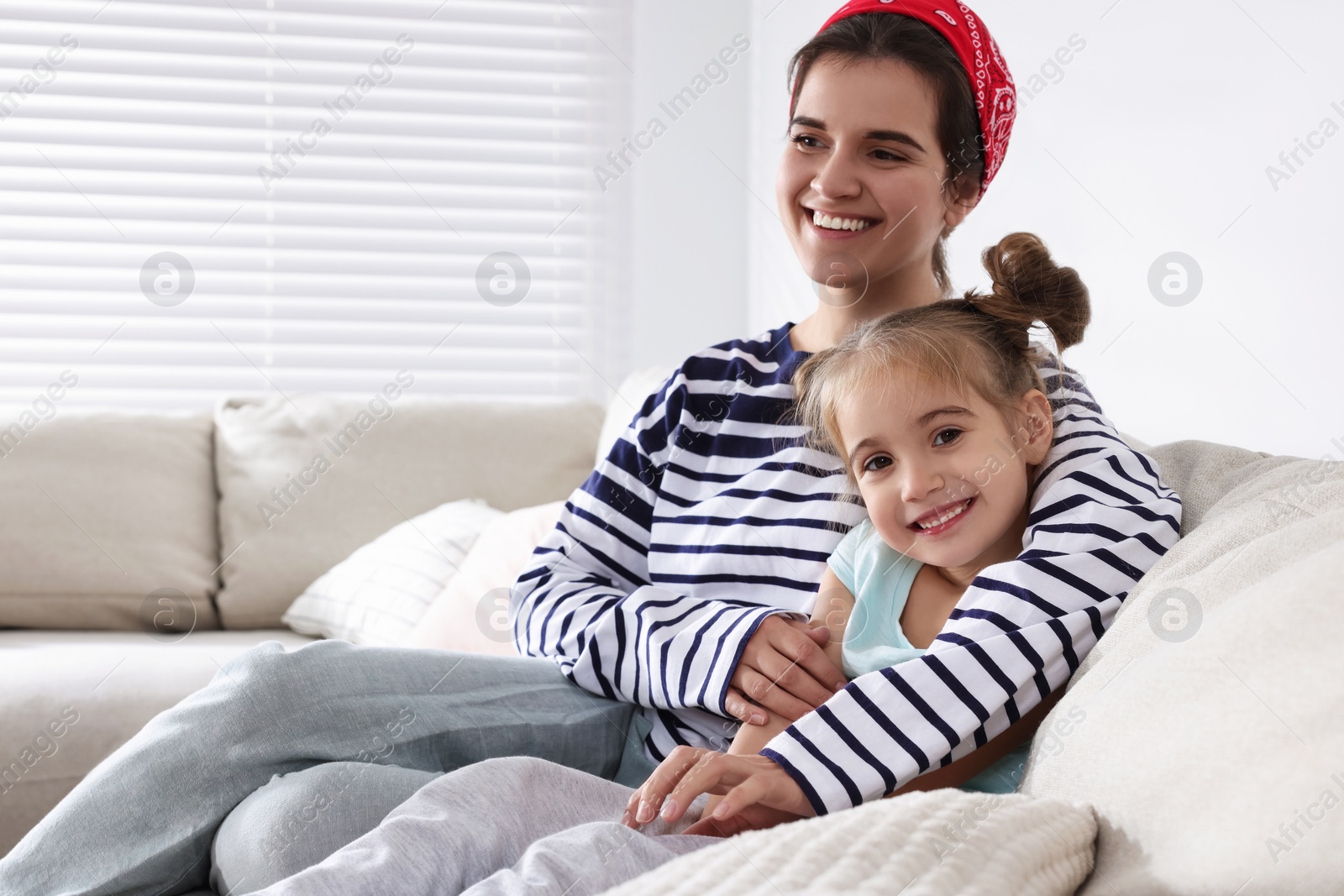 Photo of Young mother and her daughter spending time together on sofa at home