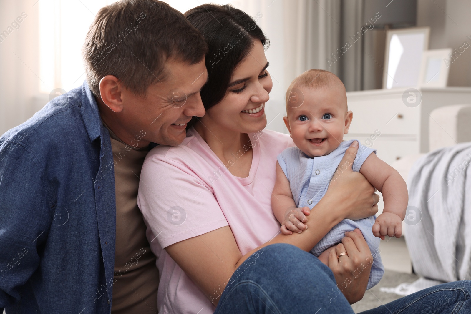 Photo of Happy family with their cute baby at home