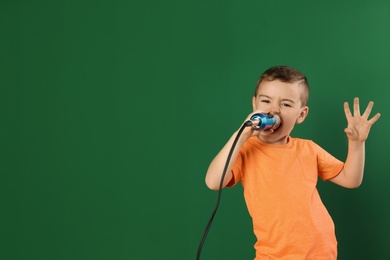 Photo of Cute funny boy with microphone on color background. Space for text