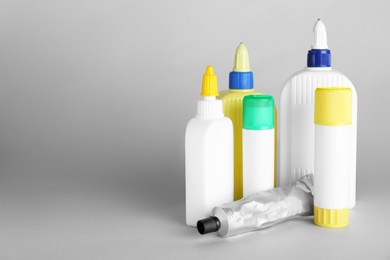 Photo of Different bottles of glue on grey background, space for text