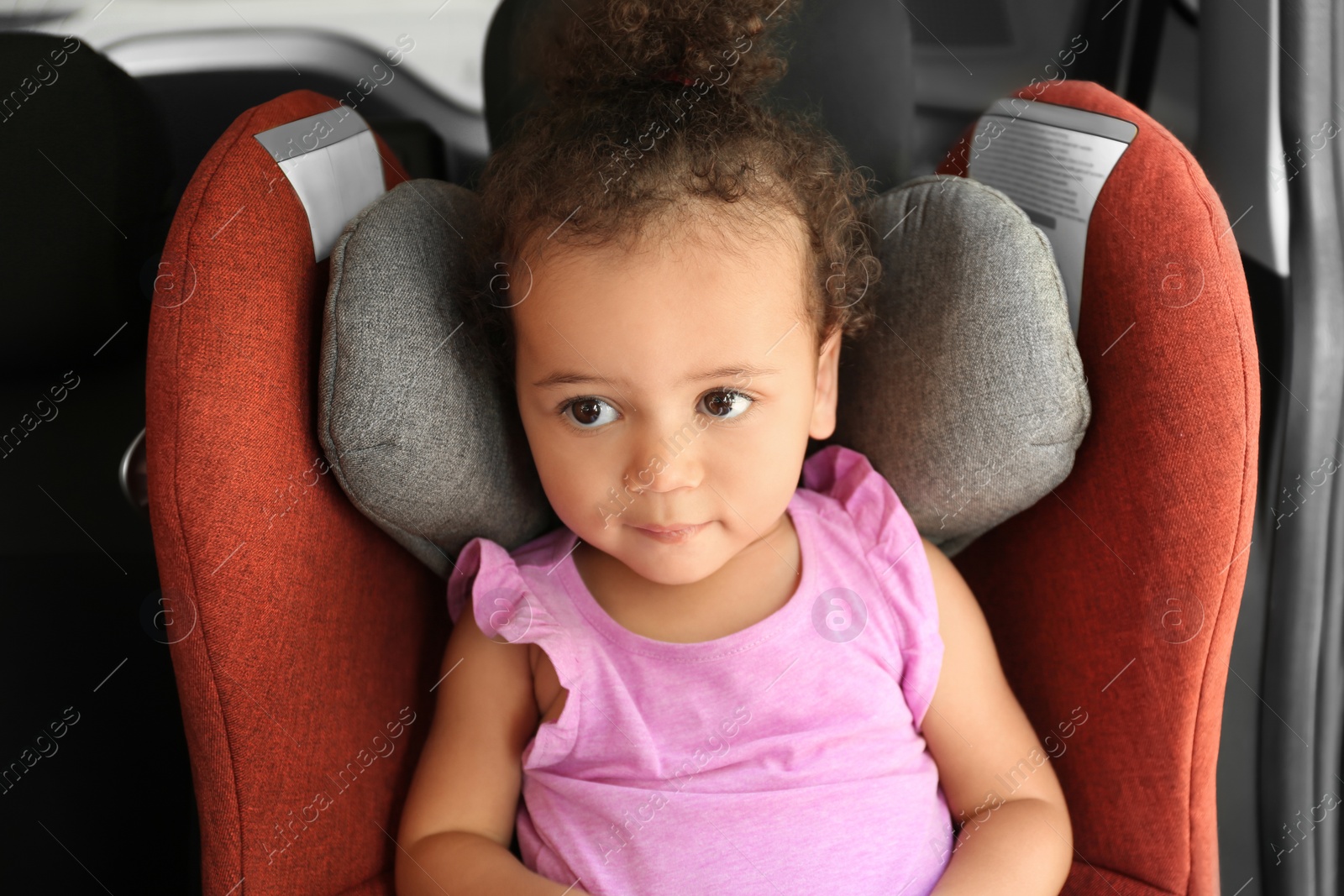 Photo of Little African-American girl in child safety seat inside of car