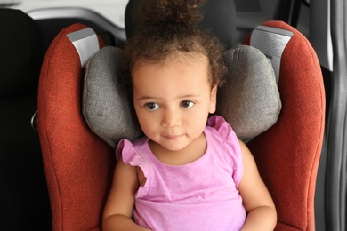 Photo of Little African-American girl in child safety seat inside of car