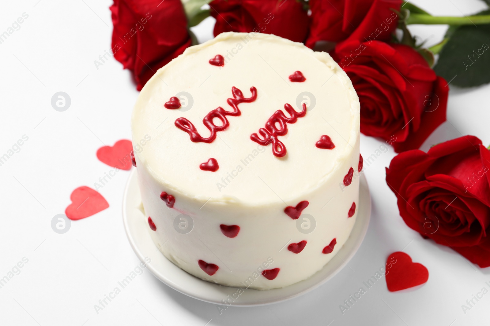 Photo of Bento cake with text Love You, paper hearts and roses on white table. St. Valentine's day surprise