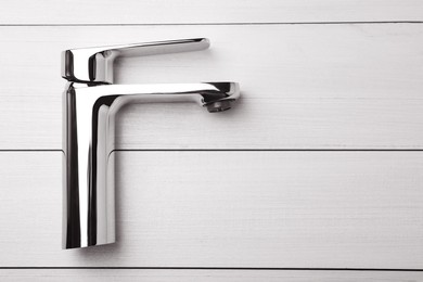 Single handle water tap on white wooden table, top view. Space for text