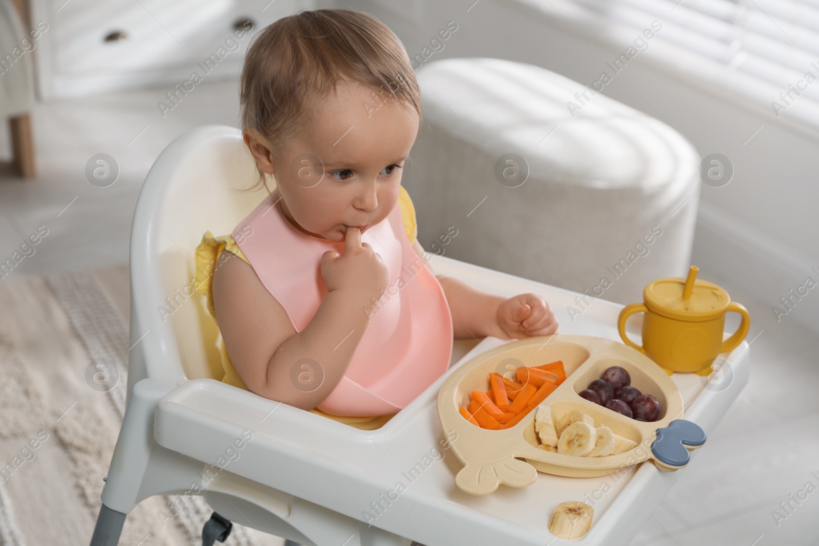 Photo of Cute little baby wearing bib while eating at home