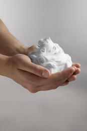 Photo of Man holding shaving foam on light grey background, closeup