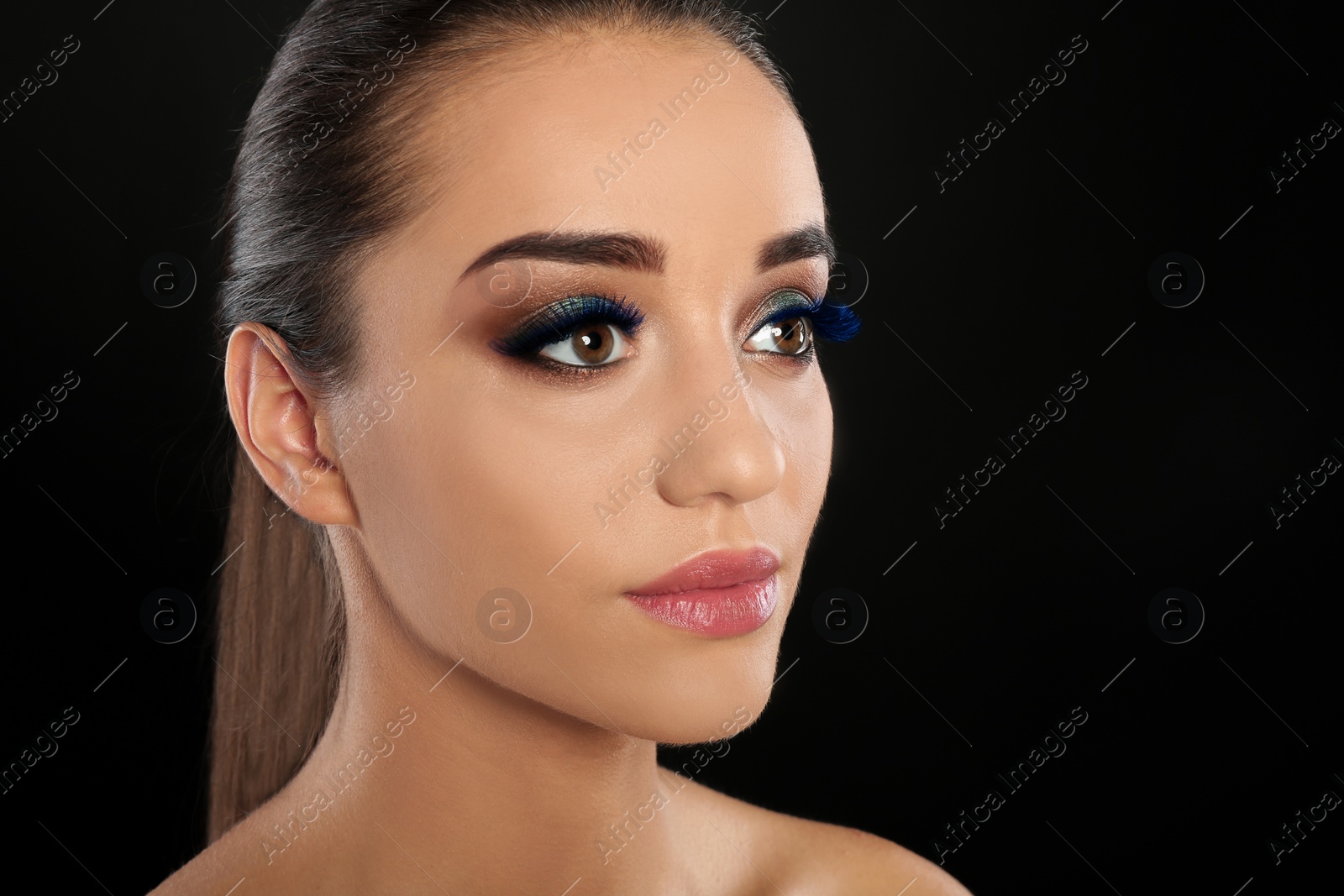 Image of Portrait of young woman with color eyelashes and beautiful makeup on black background