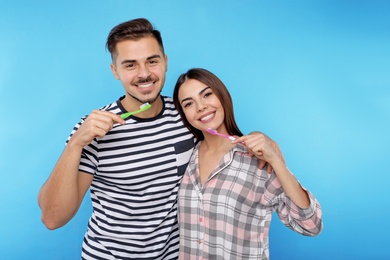 Happy couple brushing teeth on color background