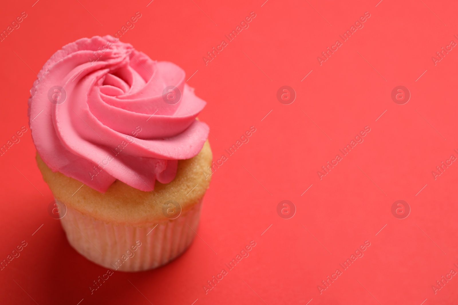 Photo of Delicious cupcake with bright cream on red background, space for text